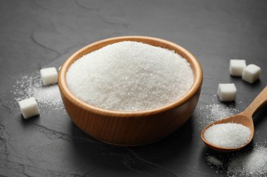 Granulated sugar in bowl on dark table clipart