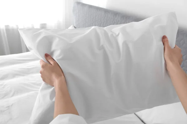 Женщина взбивает мягкую подушку в спальне, крупным планом — стоковое фото