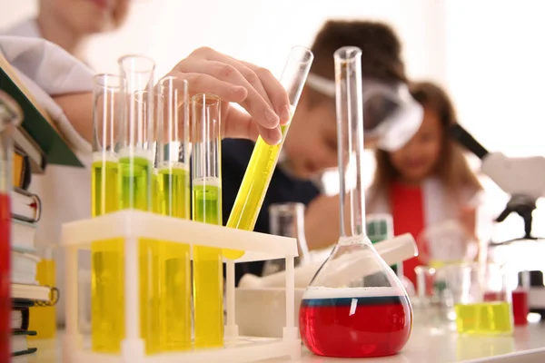 Розумні учні, які проводять експеримент в хімічному класі, зосереджуються на колбі — стокове фото