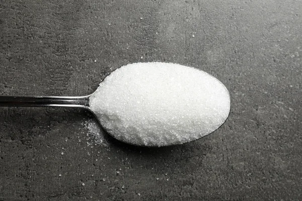 Spoon of white sugar on grey table, top view — Stok fotoğraf