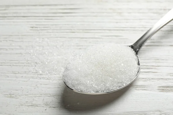 Egy kanál cukor fehér fa asztalon, közelkép — Stock Fotó