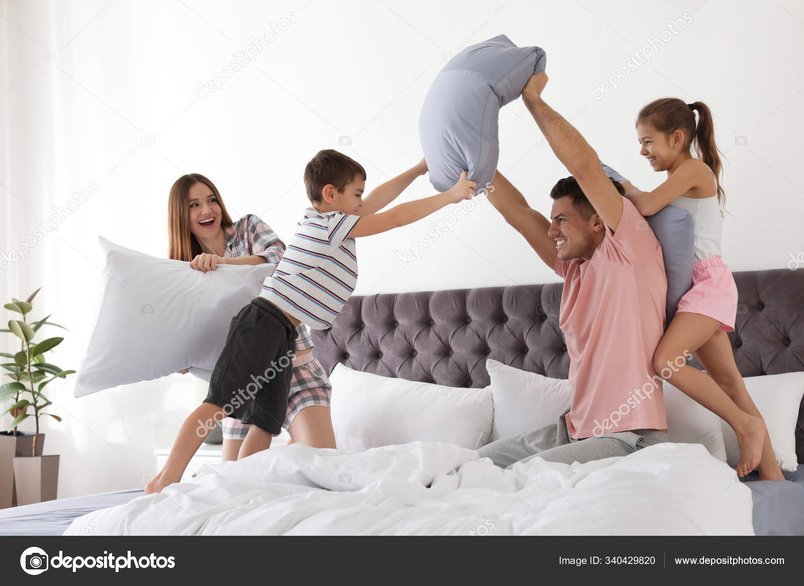 Happy family having pillow fight in bedroom Stock Photo by ©NewAfrica  340429820