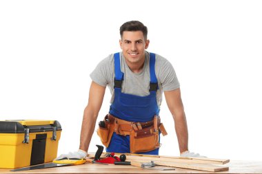 Handsome carpenter working with timber at wooden table on white 