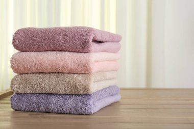 Stack of fresh towels on wooden table in bathroom. Space for text