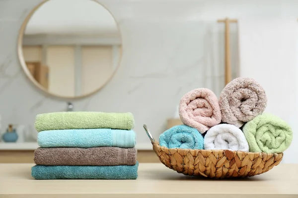 Fresh soft towels on wooden table in bathroom — Stock Photo, Image