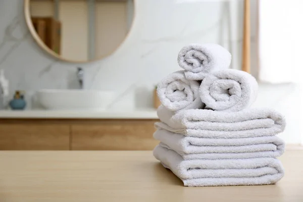 Λευκές πετσέτες σε ξύλινο τραπέζι στο μπάνιο. Χώρος για κείμενο — Φωτογραφία Αρχείου