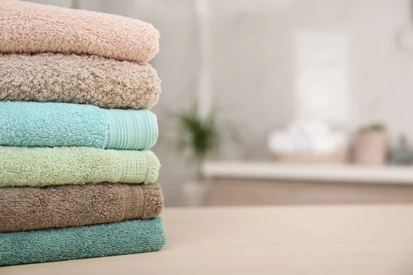 Pila di asciugamani freschi sul tavolo di legno in bagno, primo piano. Spac — Foto Stock