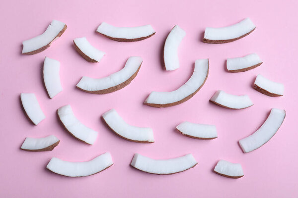 Fresh coconut pieces on pink background, flat lay