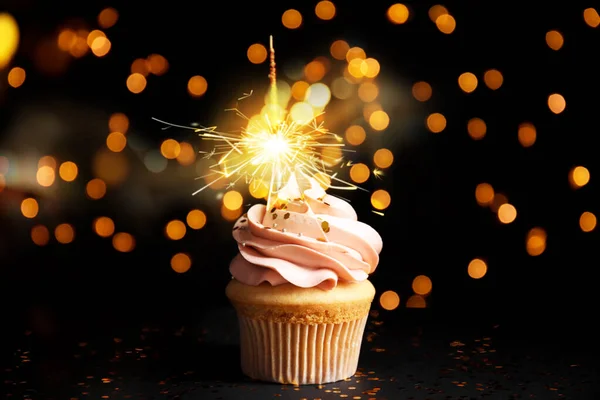 Beautiful birthday cupcake with sparkler on black table against — 스톡 사진