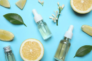 Flat lay composition with bottles of citrus essential oil on light blue background