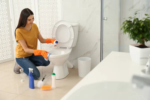 Mujer joven limpieza inodoro en el baño — Foto de Stock