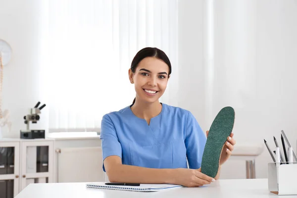 Jeune orthopédiste féminine montrant la semelle intérieure en clinique — Photo