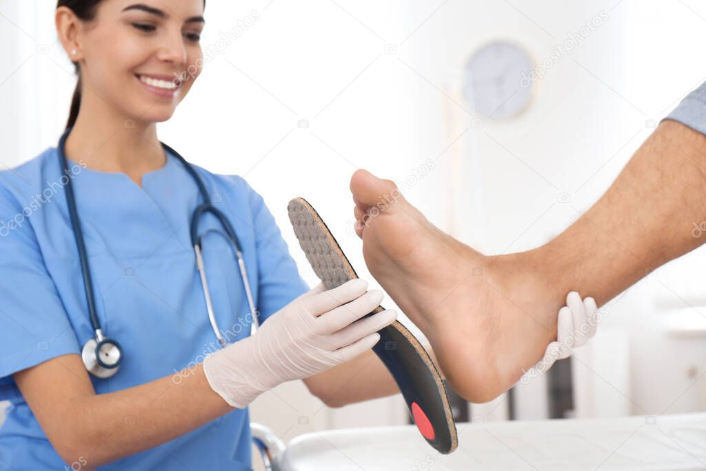 Female orthopedist fitting insole on patient's foot in clinic