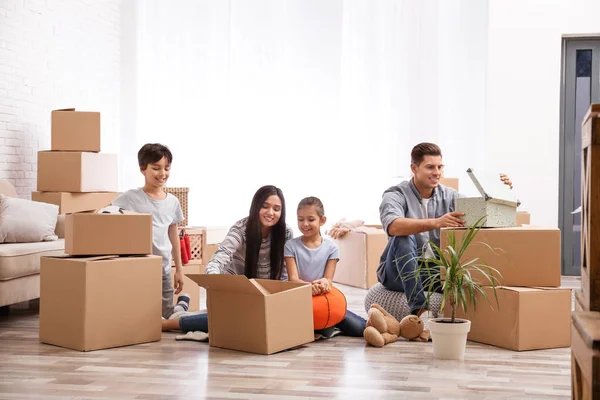 Happy family unpacking moving boxes at their new home — Stock Photo, Image