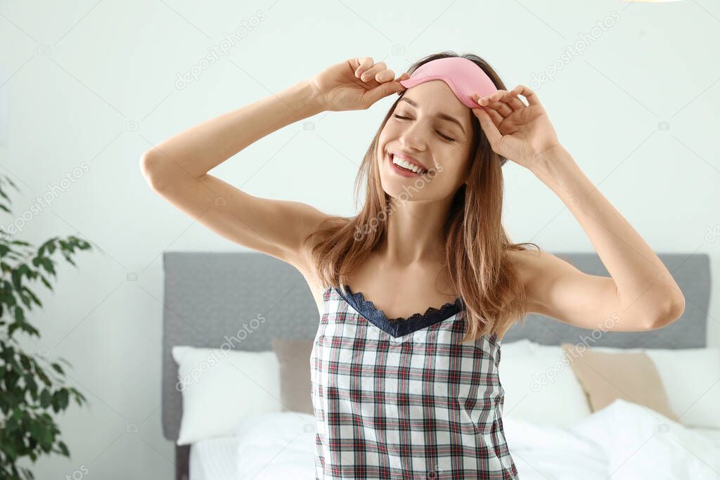 Beautiful woman wearing pajamas and sleep mask indoors. Bedtime