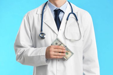 Açık mavi arka planda rüşvet alan doktor, yakın plan. Yozlaşma 