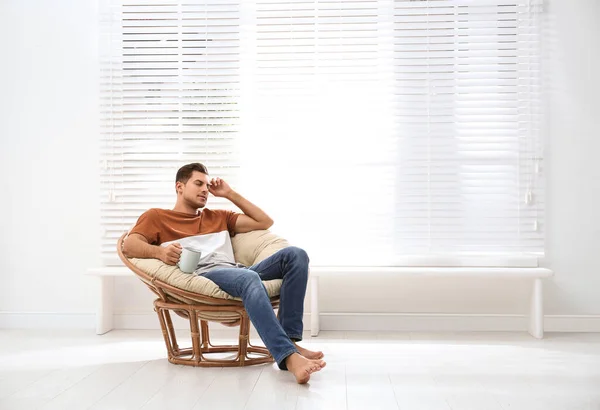 Homme attrayant relaxant dans une chaise papasan près de la fenêtre à la maison. Sp. — Photo