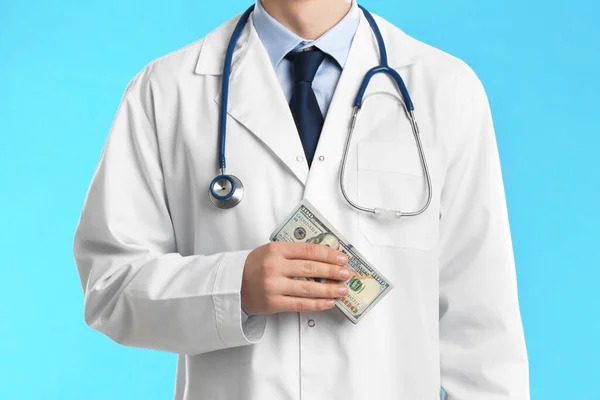 Doutor com suborno em fundo azul claro, close up. Corrupção — Fotografia de Stock