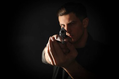 Professional killer with gun on black background