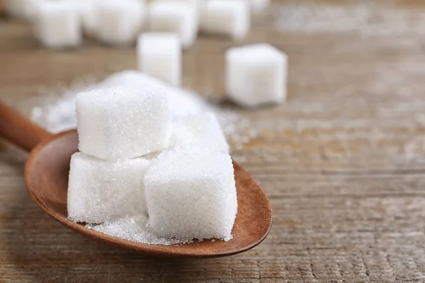 Açúcar refinado em colher em mesa de madeira, close-up. Espaço para texto — Fotografia de Stock