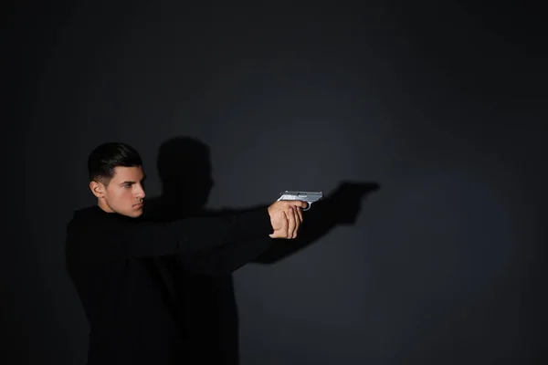 Professional killer with gun on black background — Stock Photo, Image