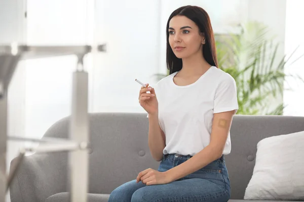 Young woman with nicotine patch and cigarette at home