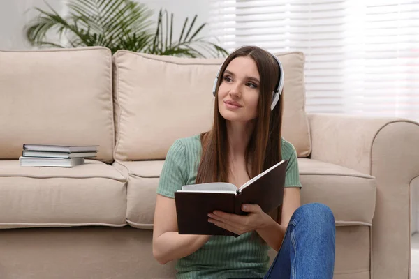 Evdeki kanepenin yanında sesli kitap dinleyen bir kadın. — Stok fotoğraf