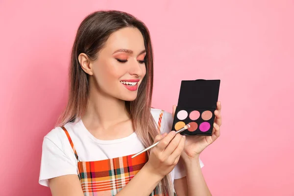 Beauty blogger with brush and eyeshadow palette on pink backgrou — Stock Photo, Image
