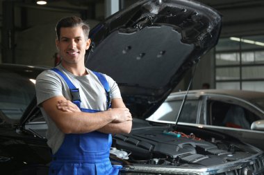 Mechanic near automobile in service center, space for text. Car diagnostic