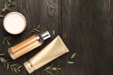 Siyah ahşap masa üzerinde kozmetik ürünlerle düz kompozisyon