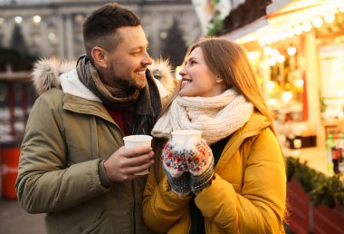 Happy couple with mulled wine at winter fair