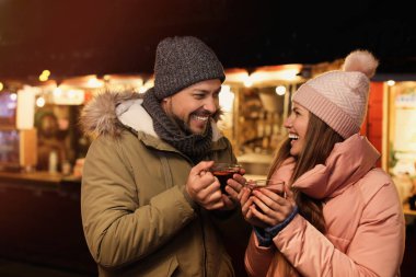Happy couple with mulled wine at winter fair
