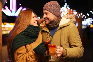 Happy couple with mulled wine at winter fair