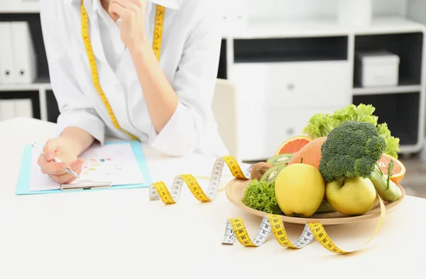Διατροφολόγος στο γραφείο με φρούτα, λαχανικά και μεζούρα — Φωτογραφία Αρχείου