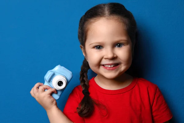 Kleiner Fotograf mit Spielzeugkamera auf blauem Hintergrund — Stockfoto