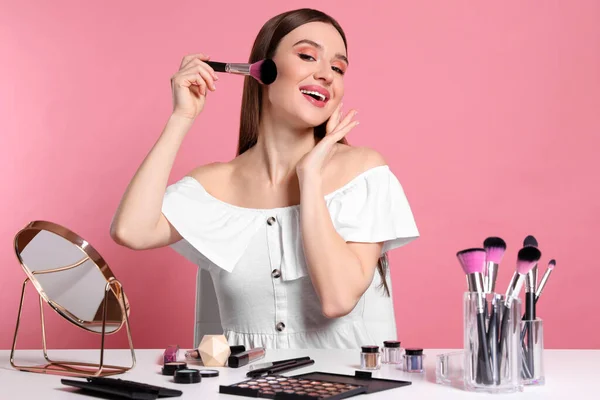 Beauty blogger dělá make-up na růžovém pozadí — Stock fotografie