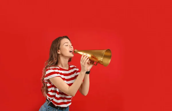 Mladá žena s megafonem na červeném pozadí — Stock fotografie