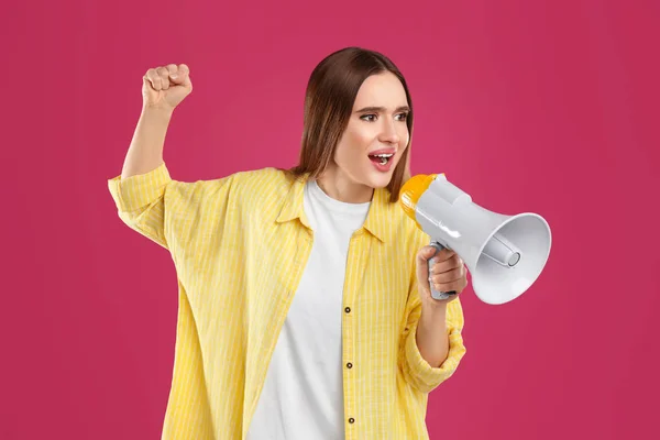 Emocionální mladá žena s megafonem na růžovém pozadí — Stock fotografie