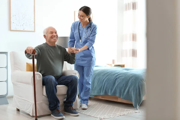 Zorgverlener helpt oudere man met stok in geriatrisch hospice — Stockfoto