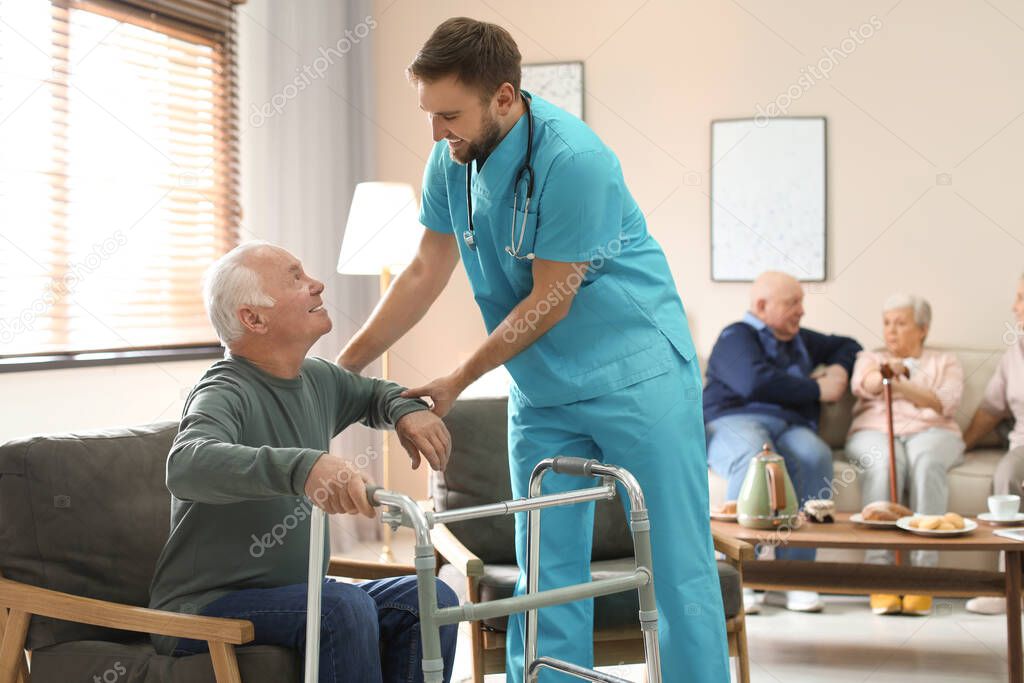 Medical worker taking care of elderly man with walker in geriatr