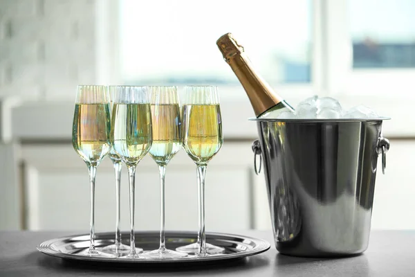 Sklenice šampaňského a kbelík na led s lahví na šedém stole — Stock fotografie