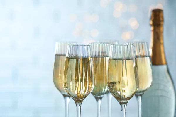 stock image Glasses and bottle of champagne against blurred lights, closeup