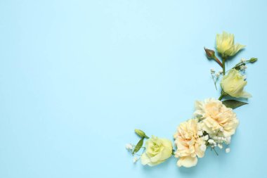 Floral composition with beautiful flowers on light blue background, flat lay. Space for text