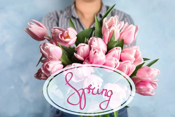 Woman with beautiful pink spring tulips on light blue background — 스톡 사진