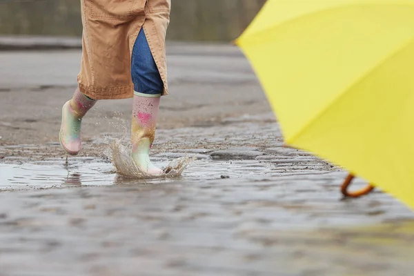 Woman in rubber boots jumping over puddle on rainy day, closeup — ストック写真
