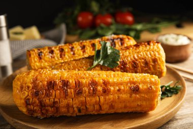 Ahşap tabakta nefis ızgara mısır koçanları, yakın plan.