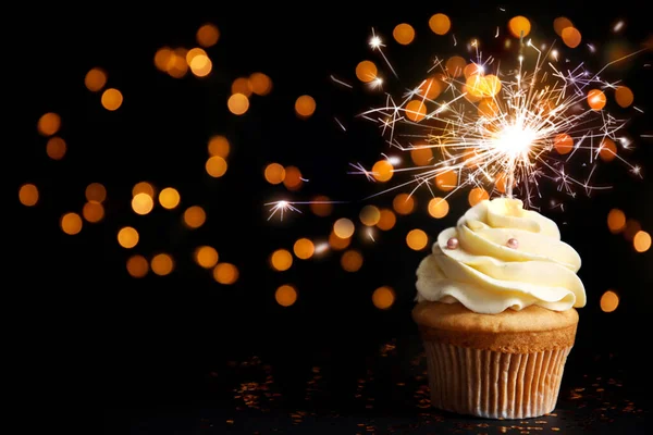 Beautiful birthday cupcake with sparkler on black table against — 스톡 사진