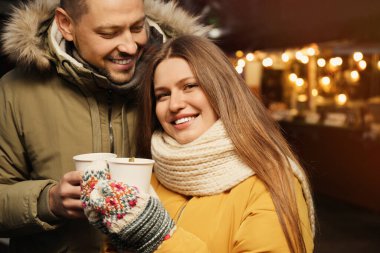 Happy couple with mulled wine at winter fair