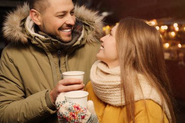 Happy couple with mulled wine at winter fair