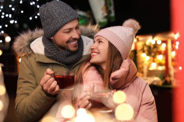 Happy couple with mulled wine at winter fair